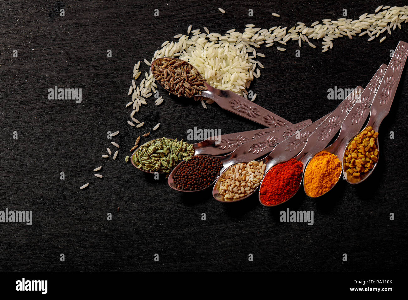 Gewürze in Löffel auf schwarzem Hintergrund Stockfoto