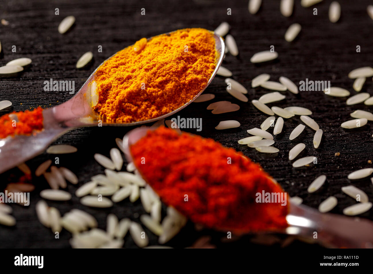 Gewürze in Löffel auf schwarzem Hintergrund Stockfoto