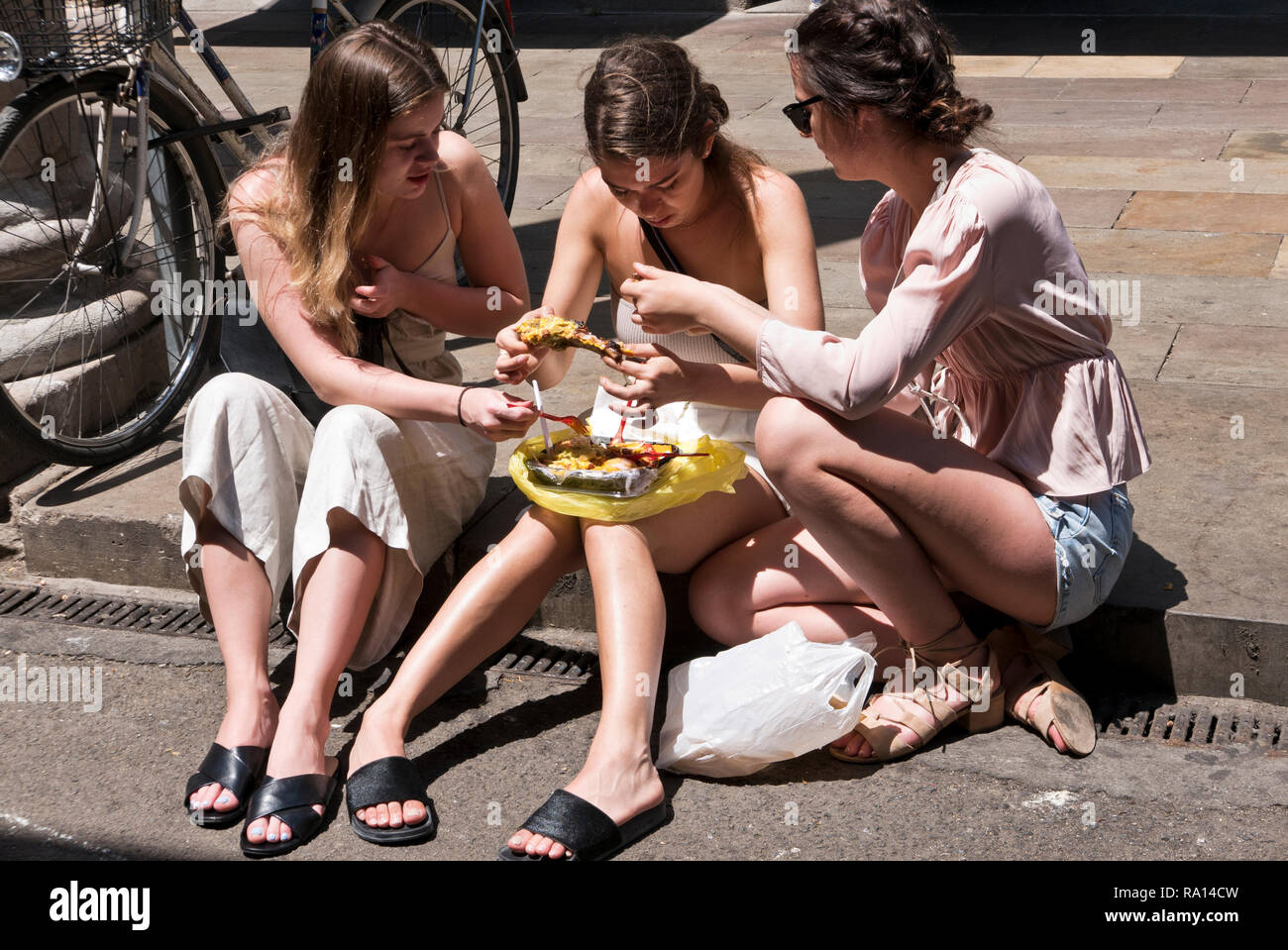 Drei junge Frau sitzt auf dem Bürgersteig und gekochtes Huhn, Barcelona, Spanien Stockfoto