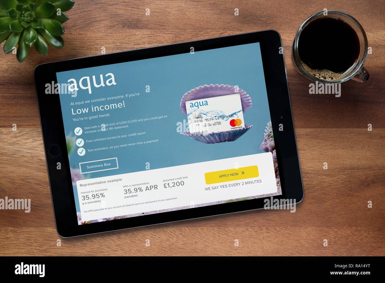 Die Website von Aqua ist auf einem iPad Tablet gesehen, auf einer hölzernen Tisch zusammen mit einem Espresso und einem Haus Anlage (nur redaktionelle Nutzung). Stockfoto