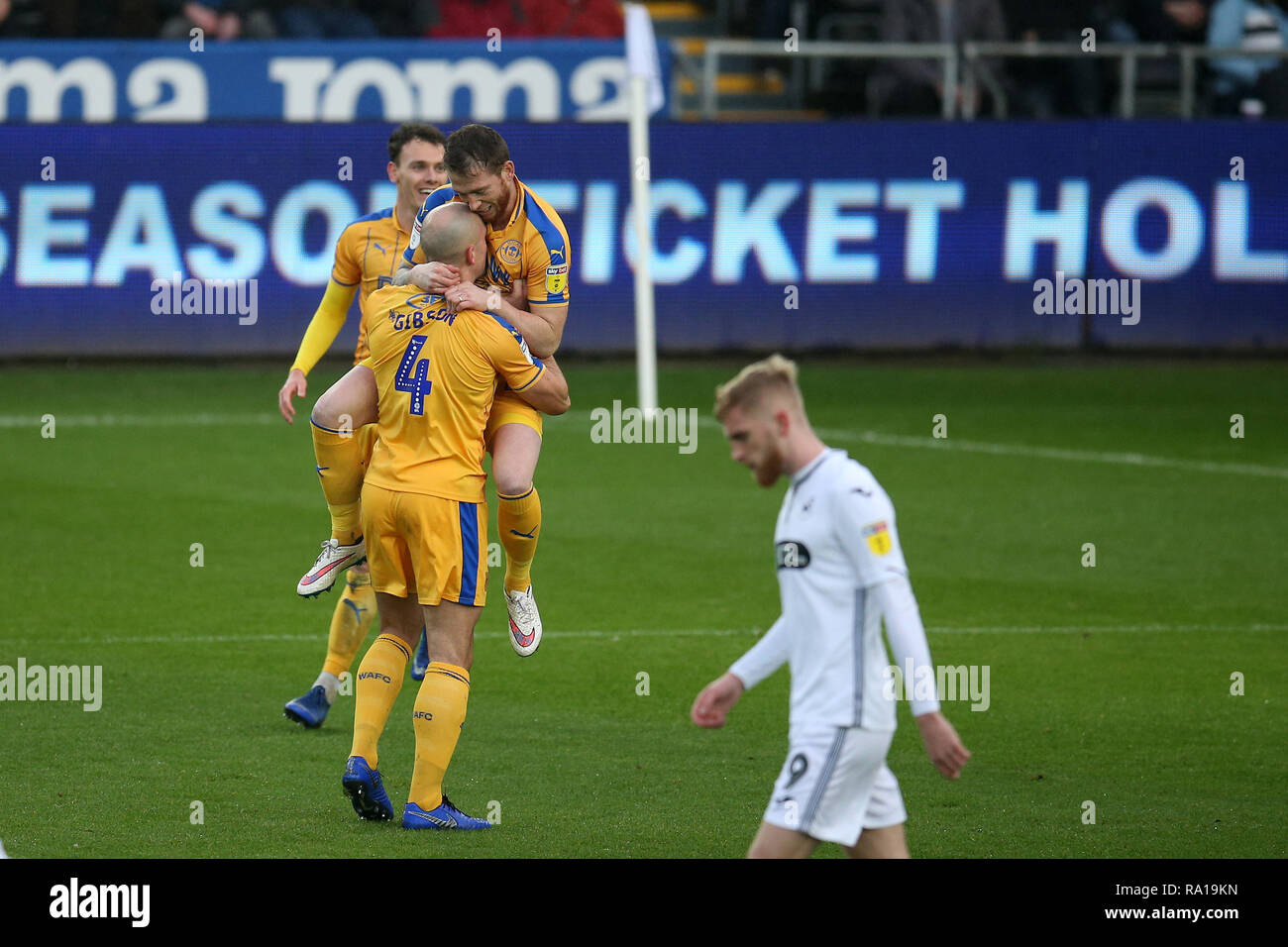 Swanswa, Wales, UK. 29. Dezember 2018. Joe Garner von Wigan Athletic © feiert mit seinen Mannschaftskameraden Darron Gibson (4), nachdem er zählt seine Mannschaften 1. Ziel von einer Strafe. EFL Skybet Meisterschaft übereinstimmen, Swansea City v Wigan Athletic in der Liberty Stadium in Swansea, Südwales am Samstag, den 29. Dezember 2018. Dieses Bild dürfen nur für redaktionelle Zwecke verwendet werden. Nur die redaktionelle Nutzung, eine Lizenz für die gewerbliche Nutzung erforderlich. Keine Verwendung in Wetten, Spiele oder einer einzelnen Verein/Liga/player Publikationen. pic von Andrew Obstgarten/Andrew Orchard sport Fotografie/Alamy leben Nachrichten Stockfoto