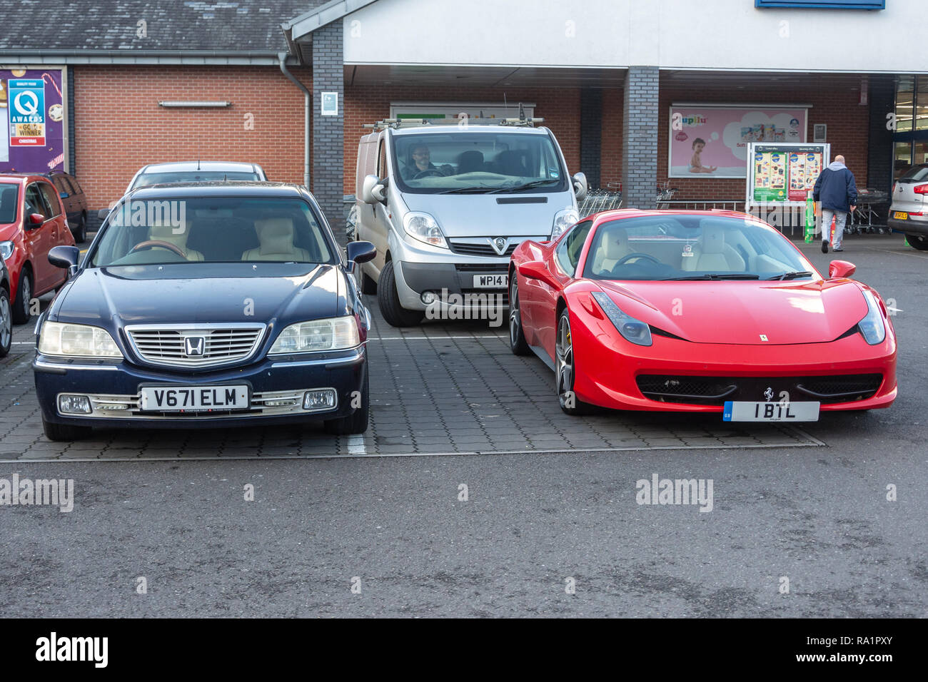 Ein paar der seltenen Autos - Ferrari 458 und Honda Legend 3,5 v6 nebeneinander auf dem Parkplatz von Lidl shop geparkt Stockfoto