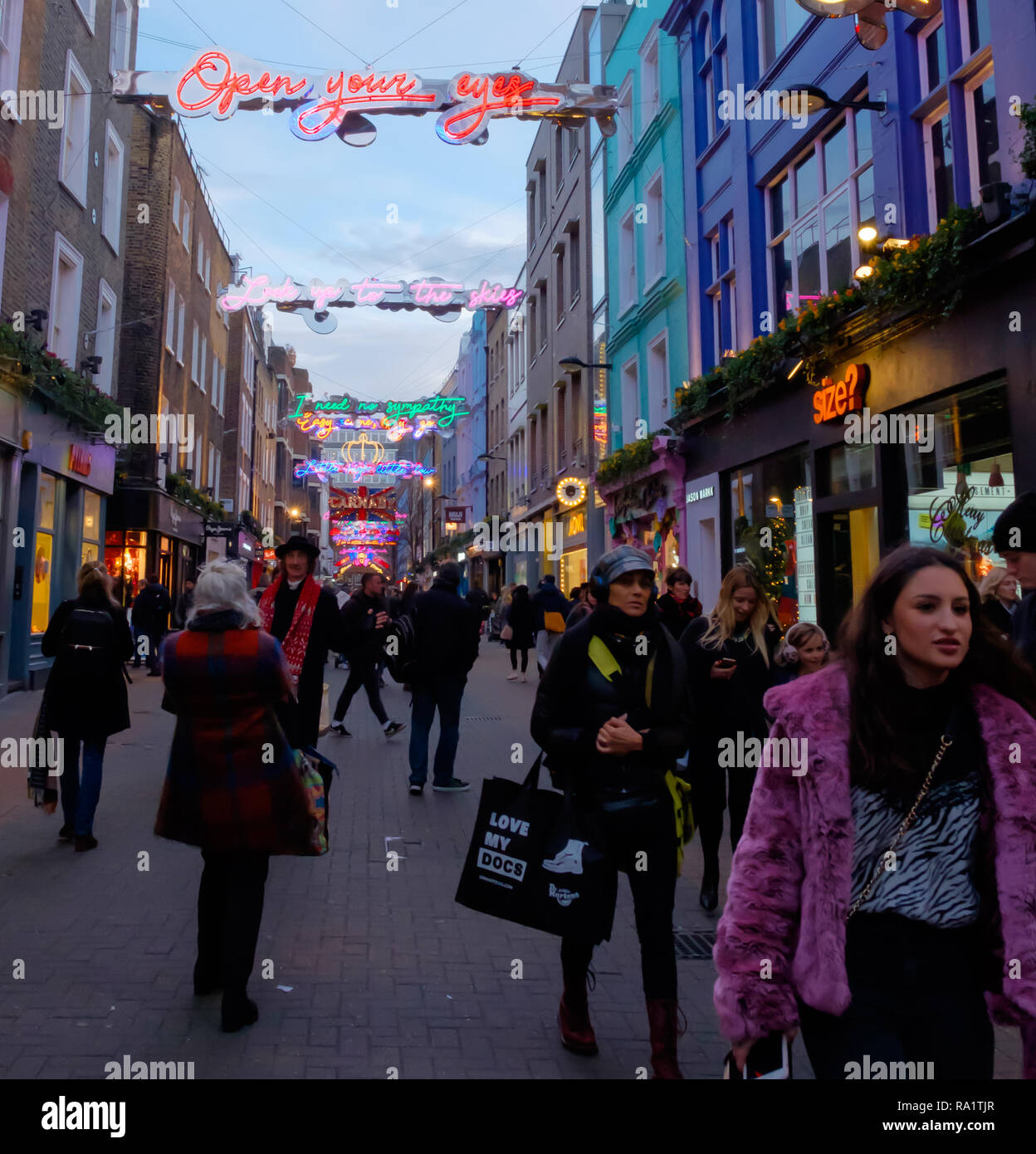 Käufer auf Carnaby Street, Soho, London unter Weihnachten Neon Licht Installation. Dezember 2018 Stockfoto