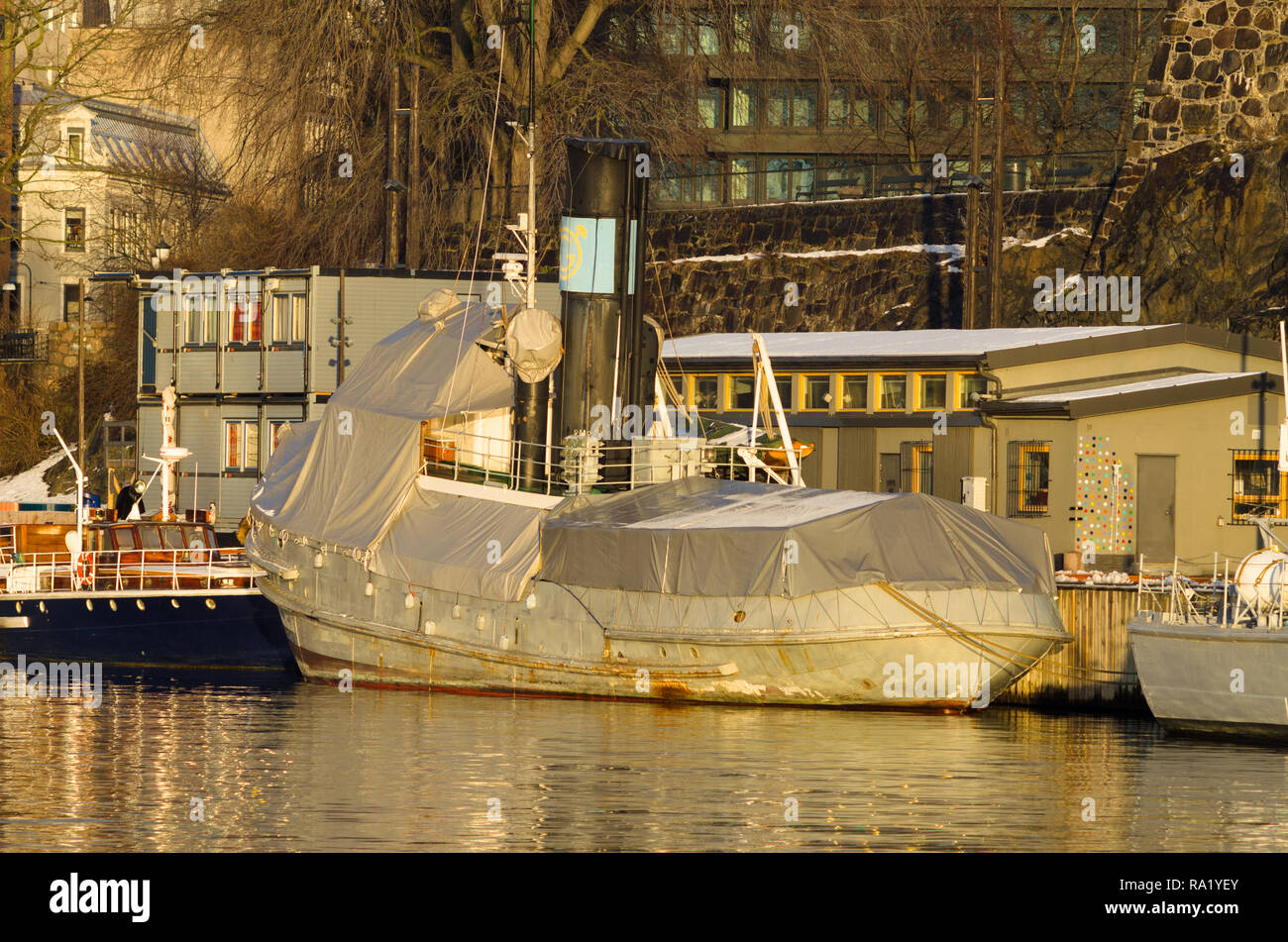 Alte pensionierte Tauziehen als Museum - Schiff in Oslo Hafen, für Kurzurlaub im Winter abgedeckt festgemacht, und teilweise mit Schnee bedeckt, mit Akershus Festung im Hintergrund. Stockfoto