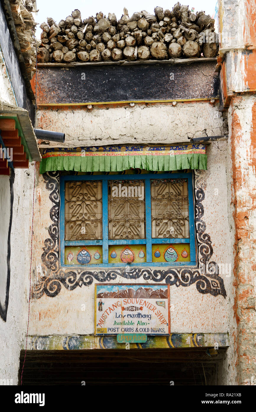 Reich verzierte Fenster an der Wand eines Tibetischen Haus in Lo Manthang, Upper Mustang, Nepal. Zeichen für einen Souvenirshop im unteren Teil des Bildes. Stockfoto