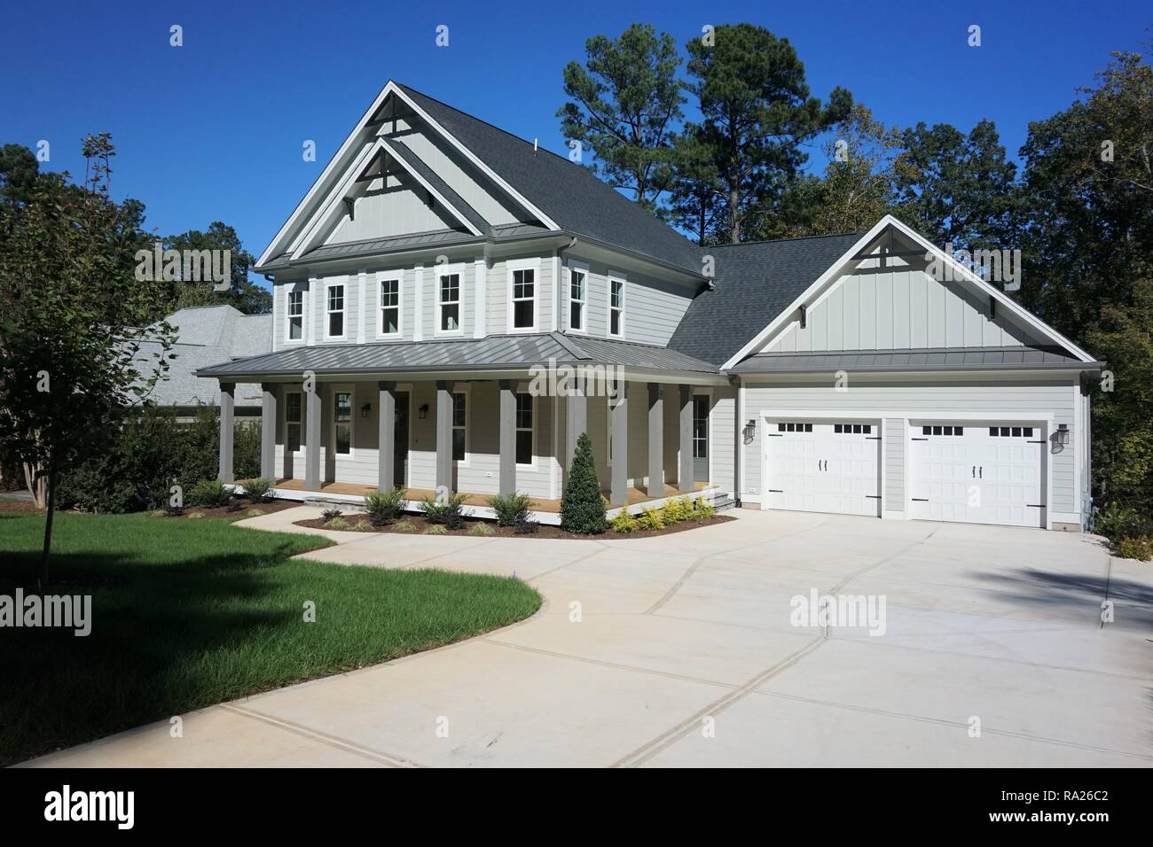Grau und Weiß. 2-stöckiges Haus mit Wrap-around-Portal in einem wohlhabenden, Suburban Nachbarschaft in North Carolina. Garage anzeigen Stockfoto