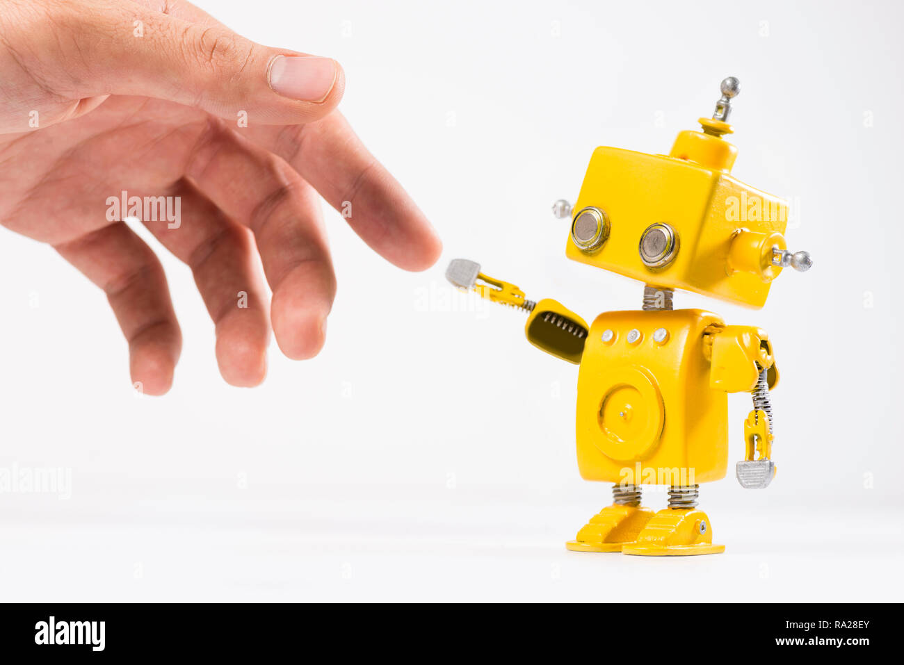 Niedlich, Gelb, handgefertigte Roboter mit einer menschlichen Hand auf einem weißen Hintergrund. Wie die Erschaffung des Adam Gemälde von Michelangelo. Stockfoto