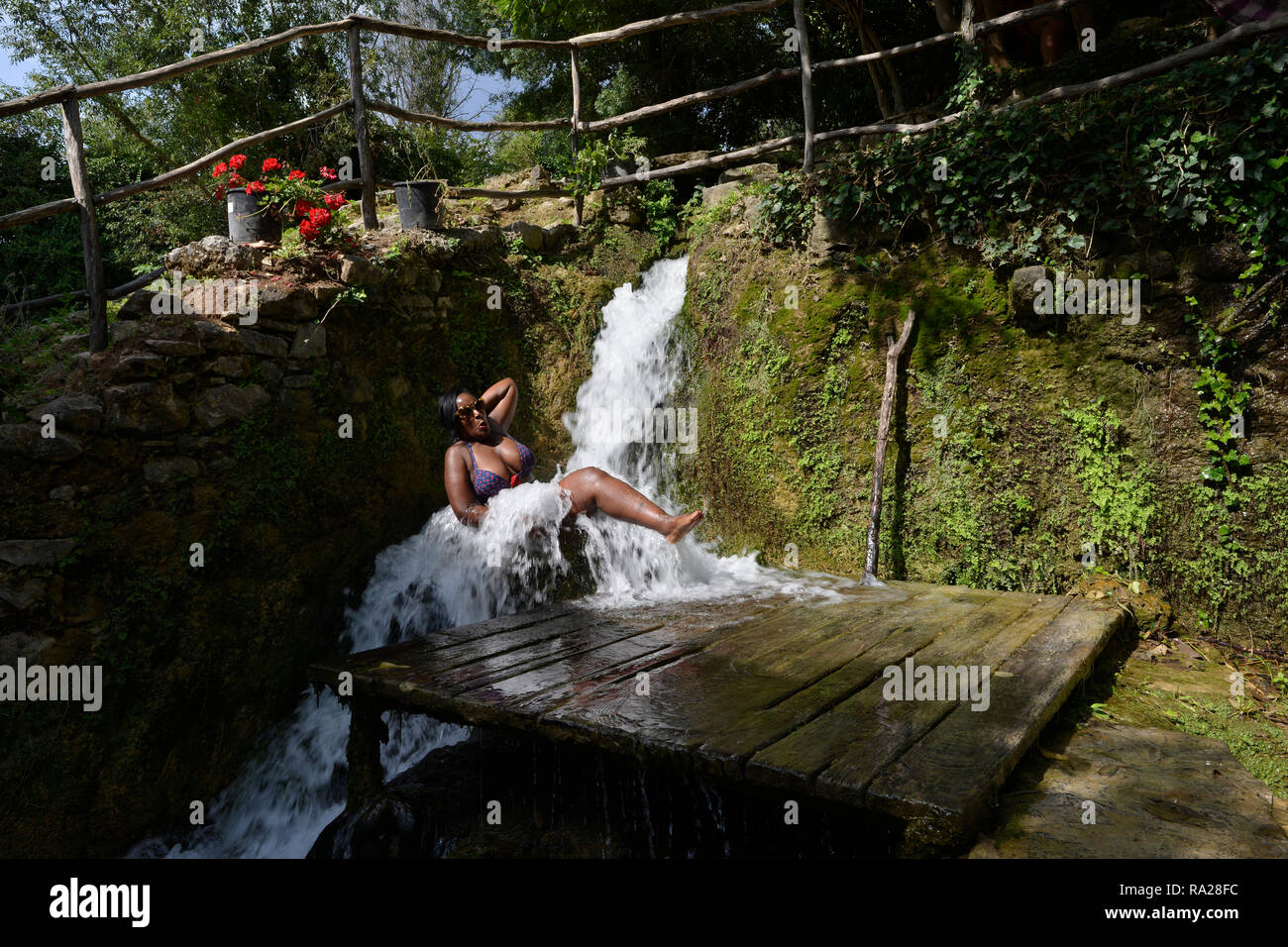 Eine schwarze Frau badet im Freien in einem Fass unter einem Wasserfall. Nationalpark Krka, Šibenik-Knin, Dalmatien, Kroatien, Europa Stockfoto