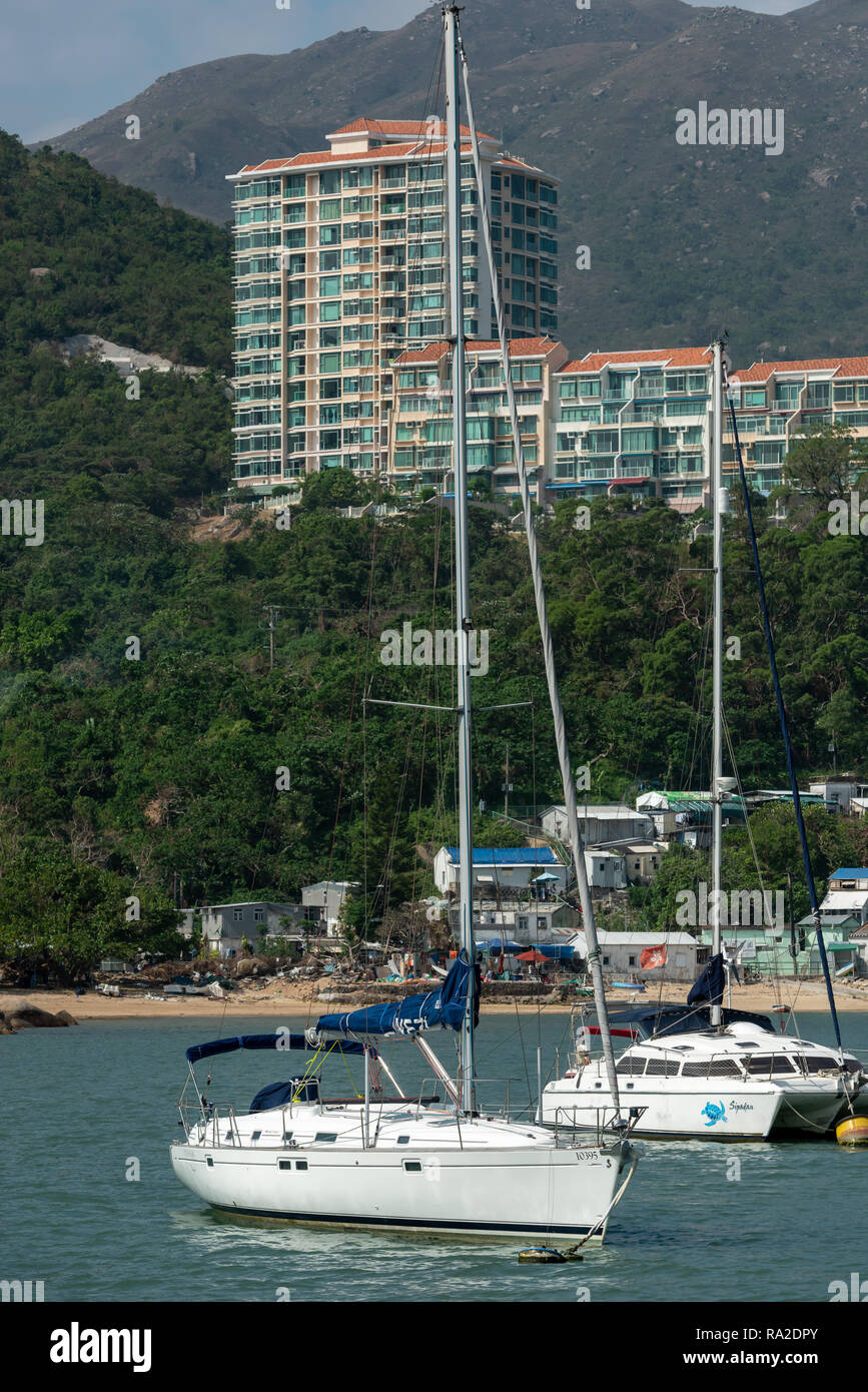 Discovery Bay Kontraste: blechhütten säumen den Strand, teure Yachten in der Bucht vor Anker, und Luxus Apartments Befehl den Hang Stockfoto
