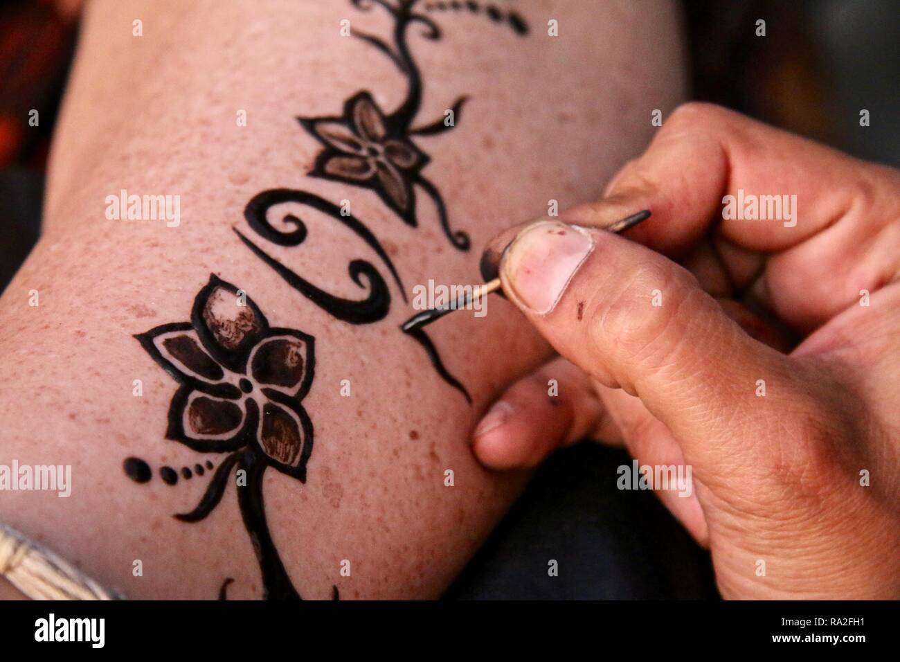 Ein Künstler Hand freestyle Zeichnung ein Henna Tattoo Design, eine Damen Bein Stockfoto