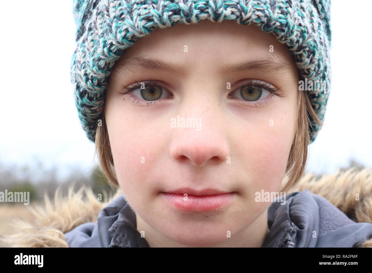Portrait eines Mädchens mit intensiven grünen Augen trägt eine Kappe im Winter kalt Stockfoto