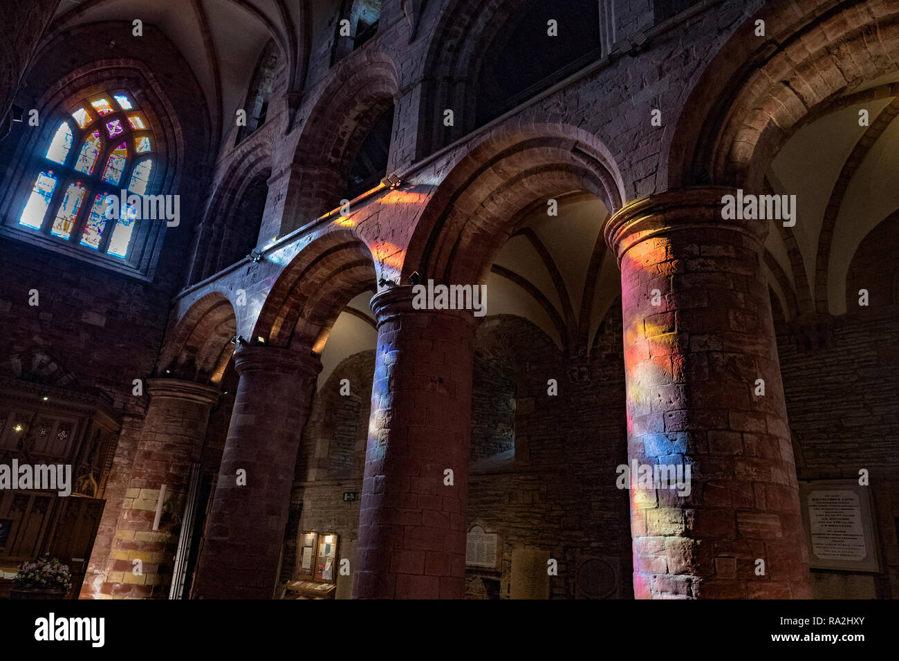Innenraum Bögen von St. Magnus Kathedrale in Kirkwall beleuchtet durch einen Regenbogen von Licht durch die Glasfenster der westlichen Fassade kommen Stockfoto