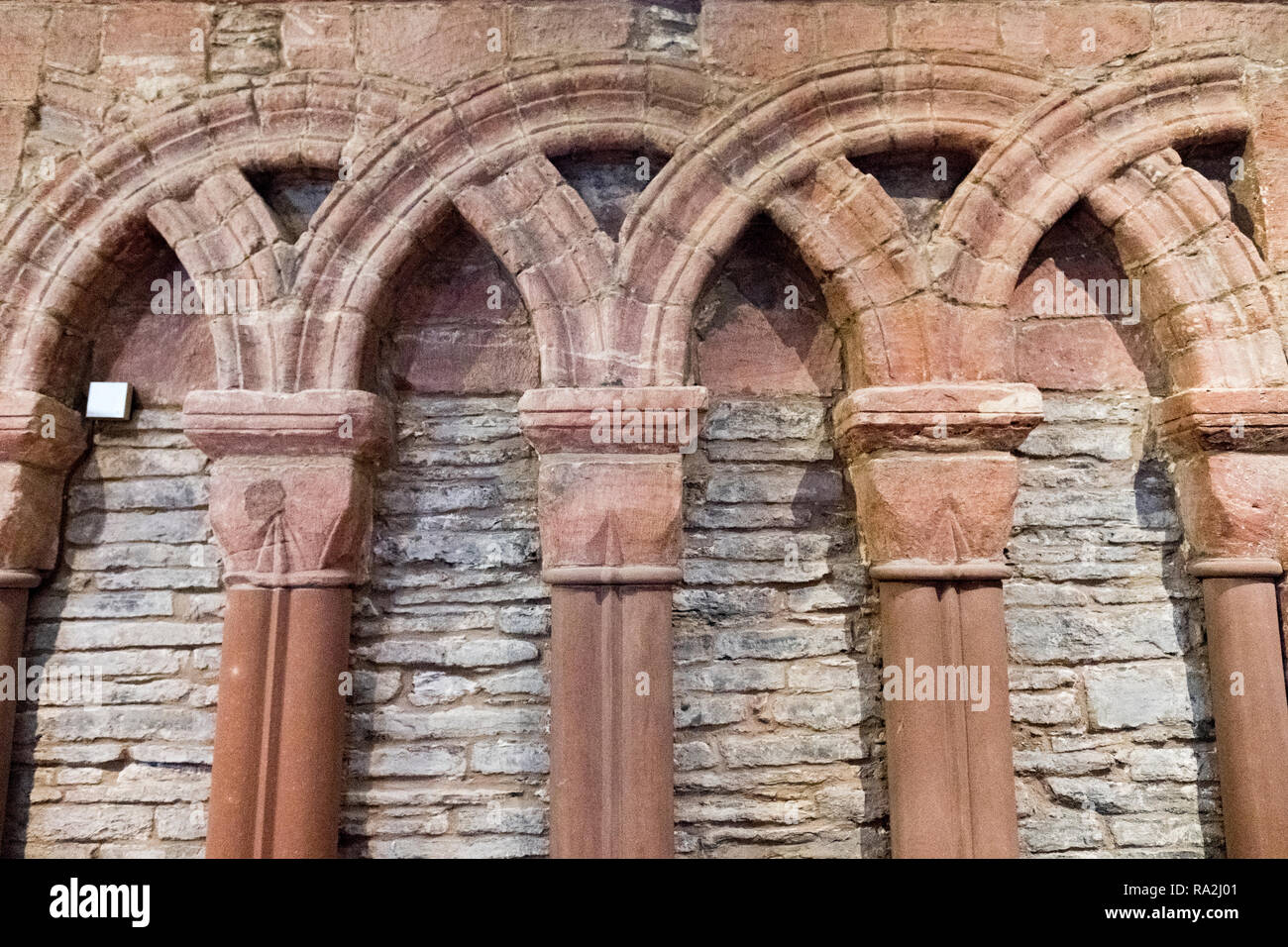 Interior Detail der verschlungenen Bögen aus mehrfarbigem in rotem Sandstein, die St. Magnus Kathedrale, Kirkwall, Orkney Inseln Stockfoto