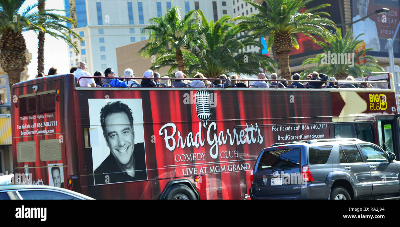 Einem oben offenen Sightseeing Tour mit dem Bus durch die BIG BUS besaß, mit Touristen geladen und umhüllt mit Werbung für das MGM Grand Comedy Club mit Verkehr und Pa Stockfoto