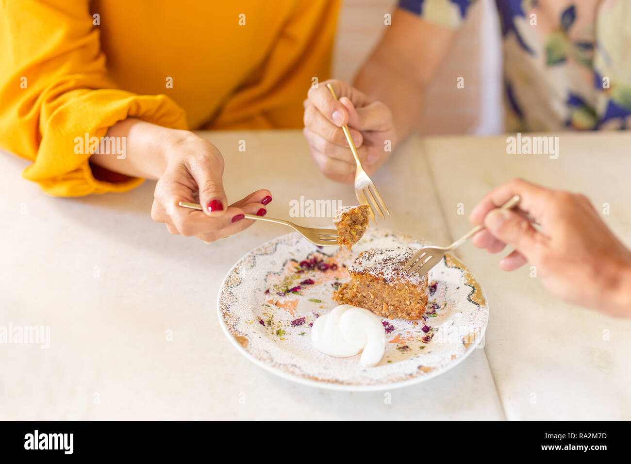 Gruppe von Freunden hand Gabel schneiden in eine Karotte Kuchen mit Puderzucker. Stockfoto