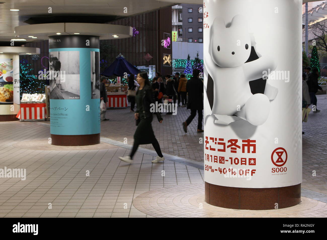 Ein Fußgänger übergibt einen Spalten Sogo Department Store, eine von ihnen ist die Werbung des Store Neues Jahr Umsatz. Bewegungsunschärfe. Stockfoto