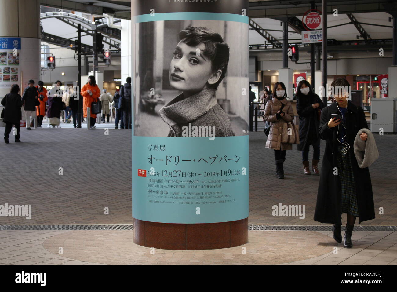 Ein Fußgänger geht eine Spalte mit einer Anzeige für eine Audrey Hepburn Ausstellung in einem Kaufhaus. Bewegungsunschärfe. Stockfoto