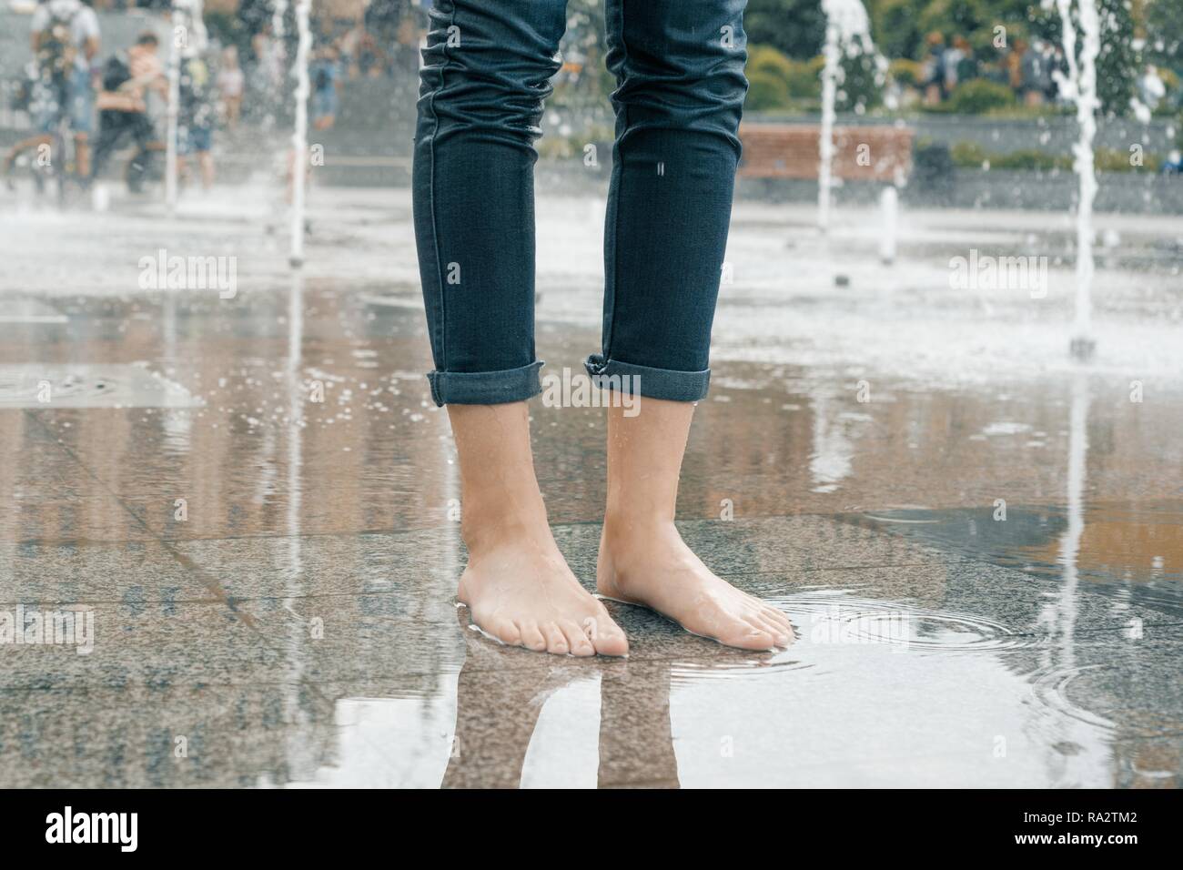 Beine von jungen Mädchen in der nassen Jeans mit Sommer Stadt Brunnen. Stockfoto