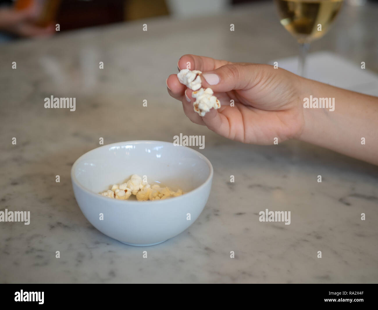 Frau gepflegten Hand packte frisches Popcorn aus einer kleinen Schüssel mit Wein Stockfoto