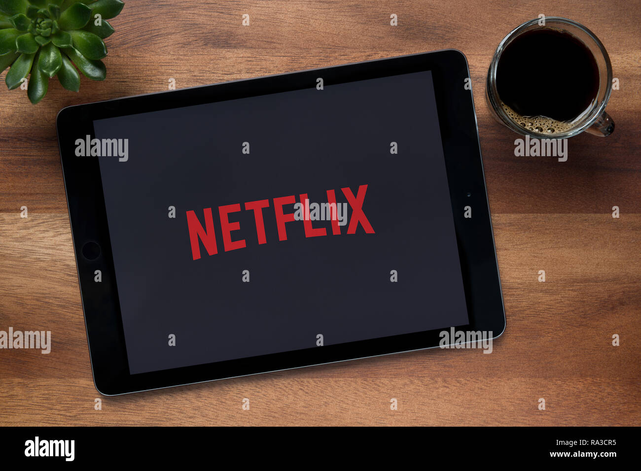 Die Netflix App auf dem iPad Tablet gesehen, auf einer hölzernen Tisch zusammen mit einem Espresso und einem Haus Anlage (nur redaktionelle Nutzung). Stockfoto