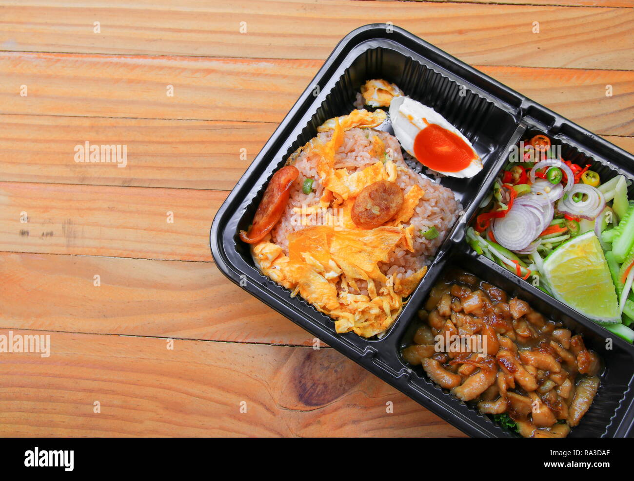 Gebratener Reis mit Garnelen paste gehören Mango, Eier, Schweinefleisch, Zwiebeln, Gemüse in Box schwarz/Thai Essen auf einem Holz Tisch Hintergrund Stockfoto