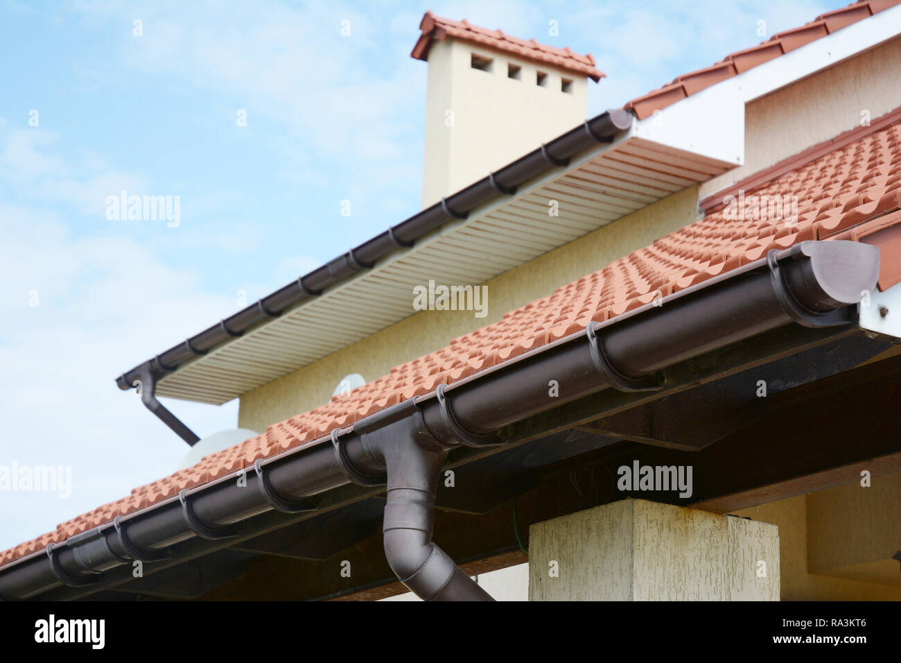 Regenrinnen System ein neues Haus mit Kamin, roter Ton Ziegeldach und Giebel und Tal Art der Dachkonstruktion Stockfoto