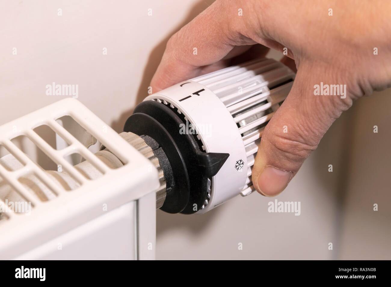 Hand passt die Temperatur am Thermostat der Heizung, Bayern, Deutschland Stockfoto