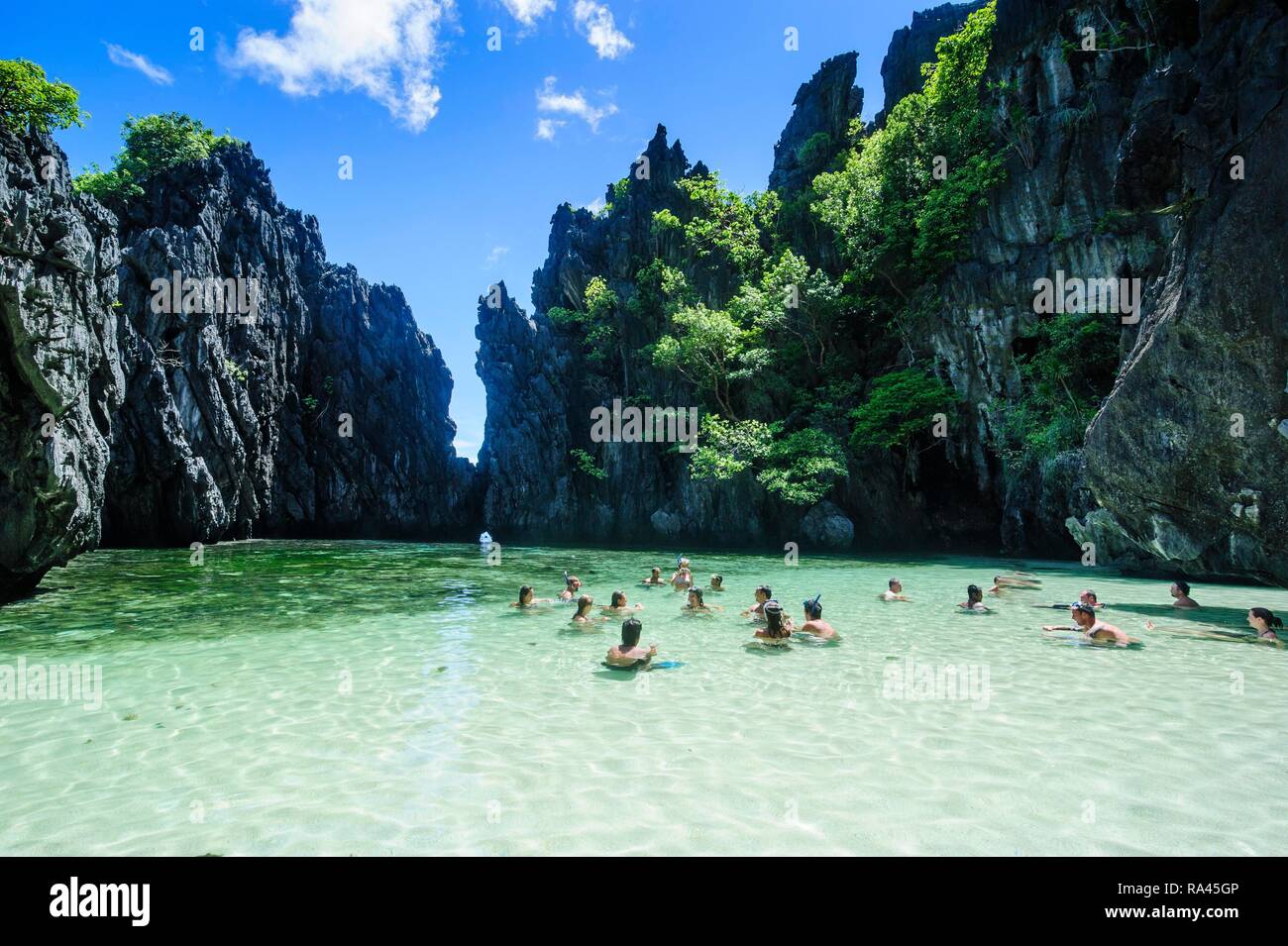 Touristen schwimmen in der versteckten Bucht mit kristallklarem Wasser in der Bacuit Archipel, Palawan, Philippinen Stockfoto