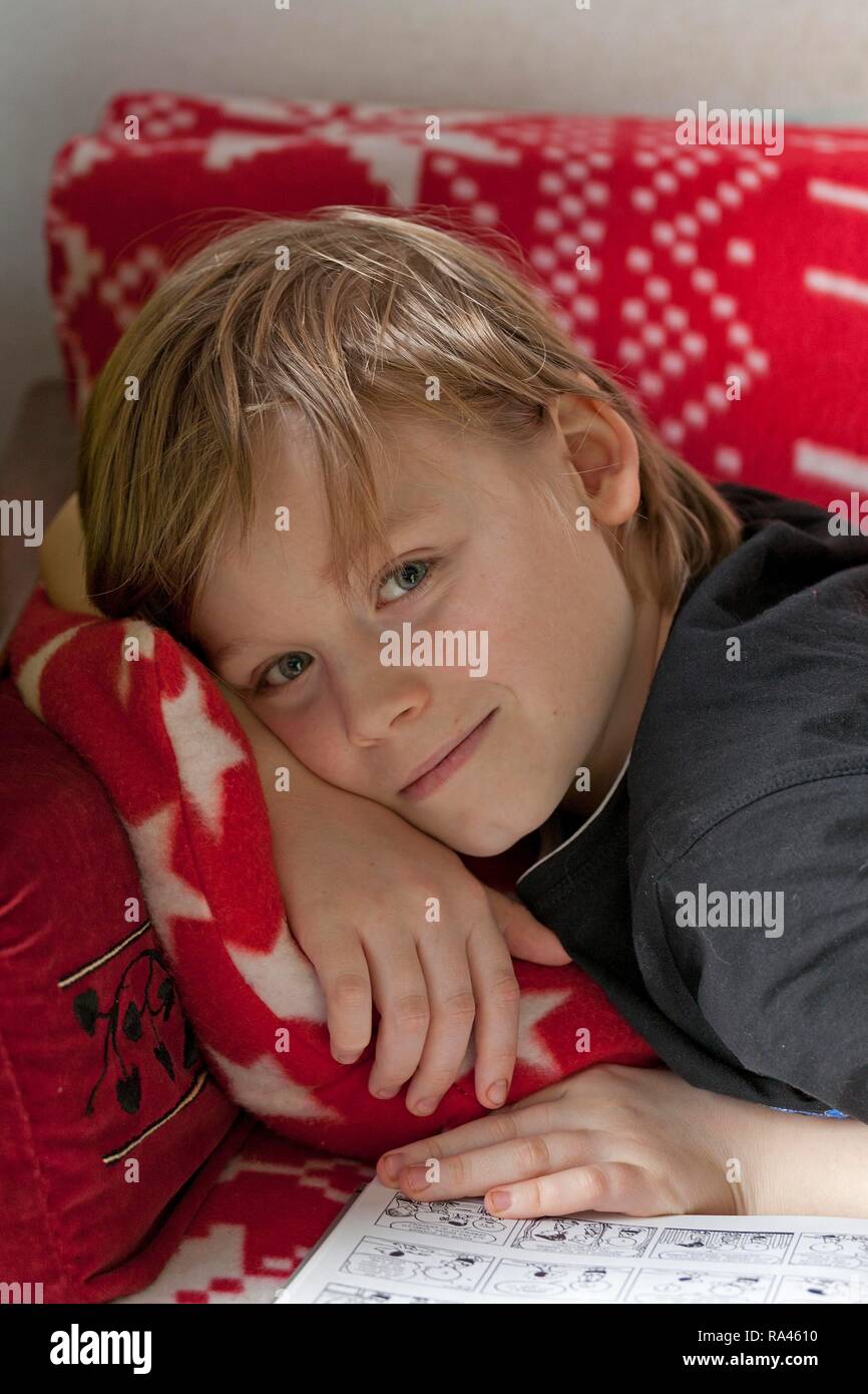 Junge auf dem Sofa mit einem Comic, Porträt Stockfoto