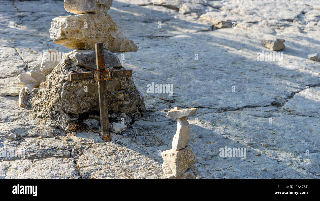 Kleine Metall kreuz und gestapelte Steine auf dem Pilgerweg zum Montecastello in Italien Stockfoto