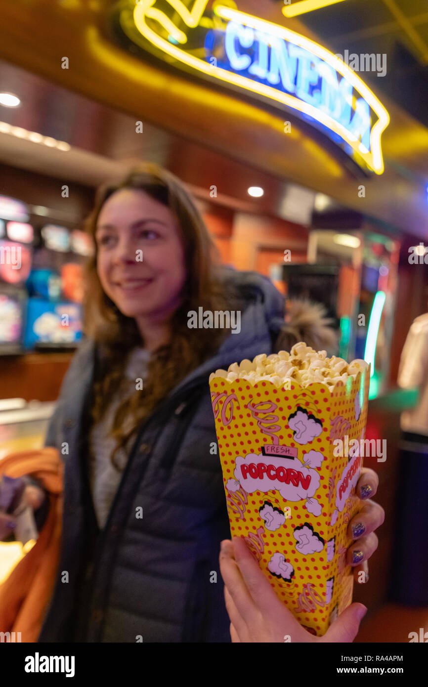 Dame vorbei an jemand Popcorn in einem alten Kino, viel Neonlicht. Stockfoto