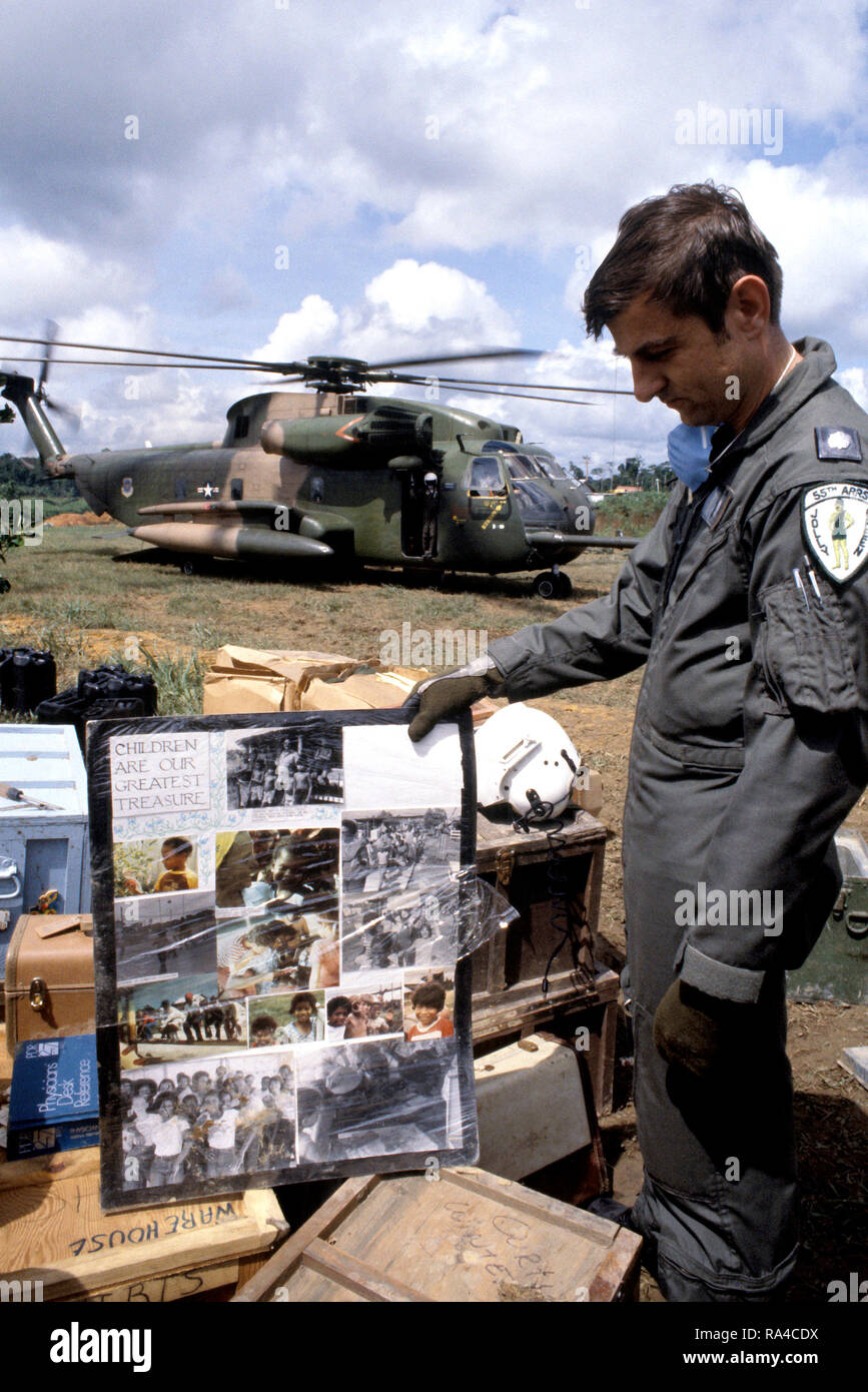 1978 - Oberstleutnant (LTC) Leonard Morrisey, ein HH-53 Jolly Green Giant Hubschrauberpiloten aus dem 55. Luft- und Raumfahrt Rescue & Recovery Squadron, untersucht ein Plakat an der Verbindung gefunden als die Überreste der Opfer der Jonestown Tragödie an Bord der Hubschrauber geladen werden. Stockfoto