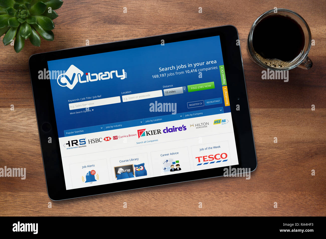 Die Website von CV-Bibliothek ist auf einem iPad Tablet gesehen, auf einer hölzernen Tisch zusammen mit einem Espresso und einem Haus Anlage (nur redaktionelle Nutzung). Stockfoto