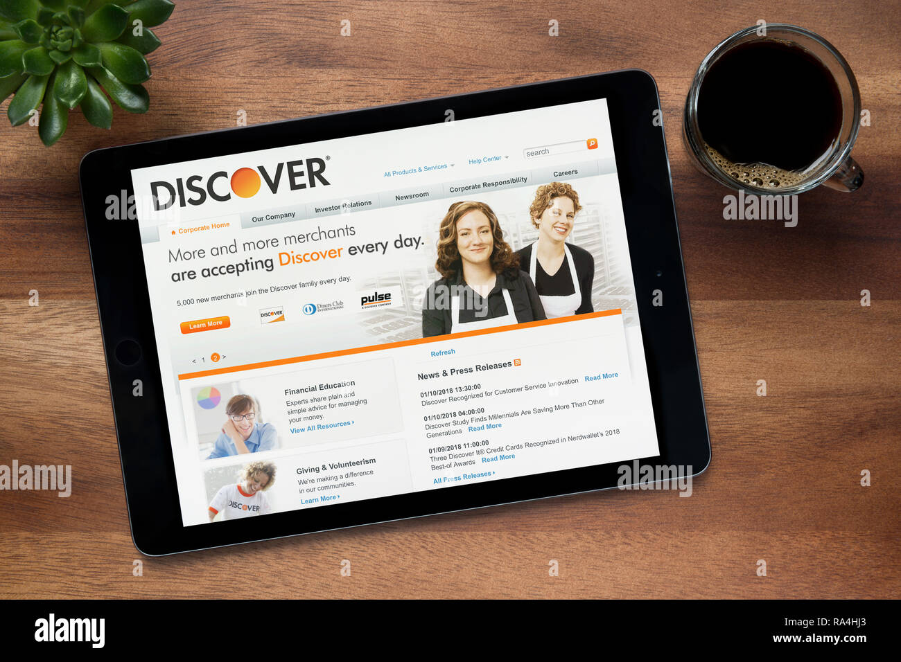 Die Website von Discover.com ist auf einem iPad Tablet gesehen, auf einer hölzernen Tisch zusammen mit einem Espresso und einem Haus Anlage (nur redaktionelle Nutzung). Stockfoto
