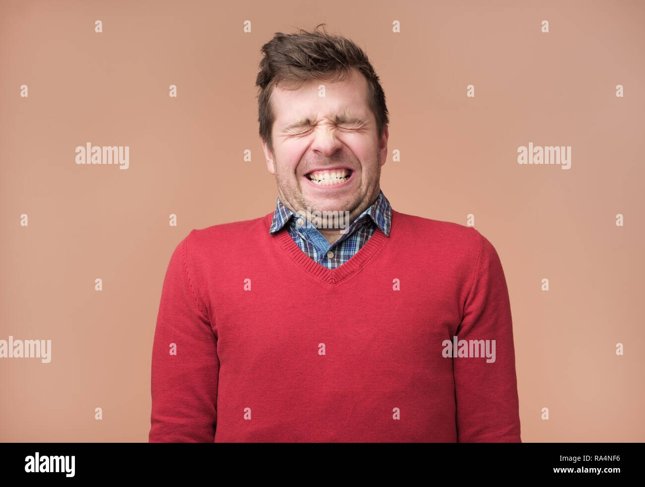 Guy grinst Kamera, zeigt weiße Zähne, schließt eyeswaiting für Geschenk Stockfoto