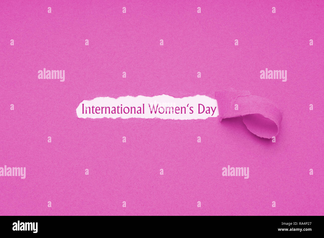 Internationaler Tag der Frauen wird am 8. März - Text vom Loch in rosa Papier Hintergrund zerrissen offenbart gefeiert. Stockfoto