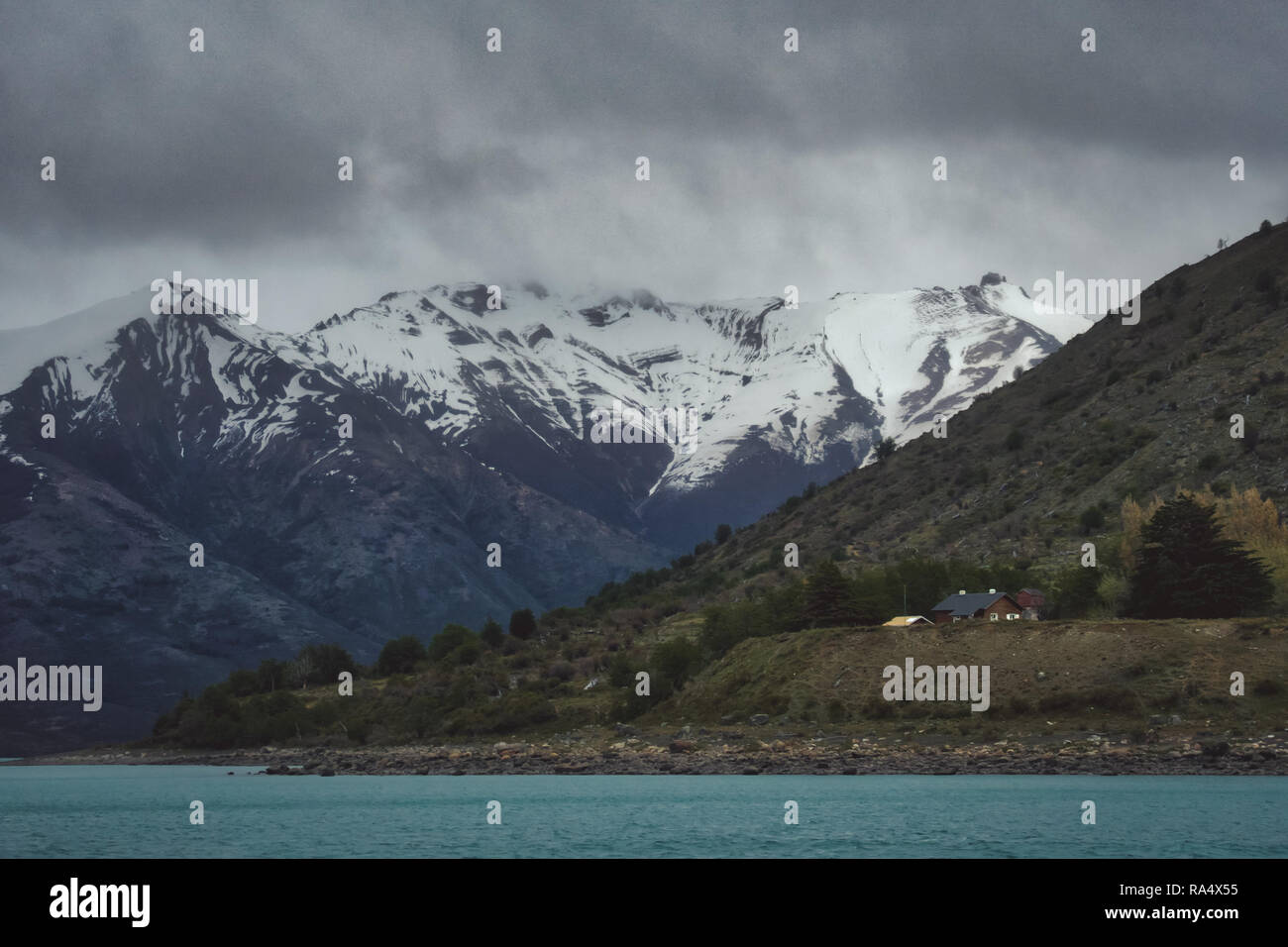 Robuste schneebedeckten Gipfeln, Argentinien über einen blauen Schmelzen Wasser See mit bedecktem Himmel und Wolken Stockfoto