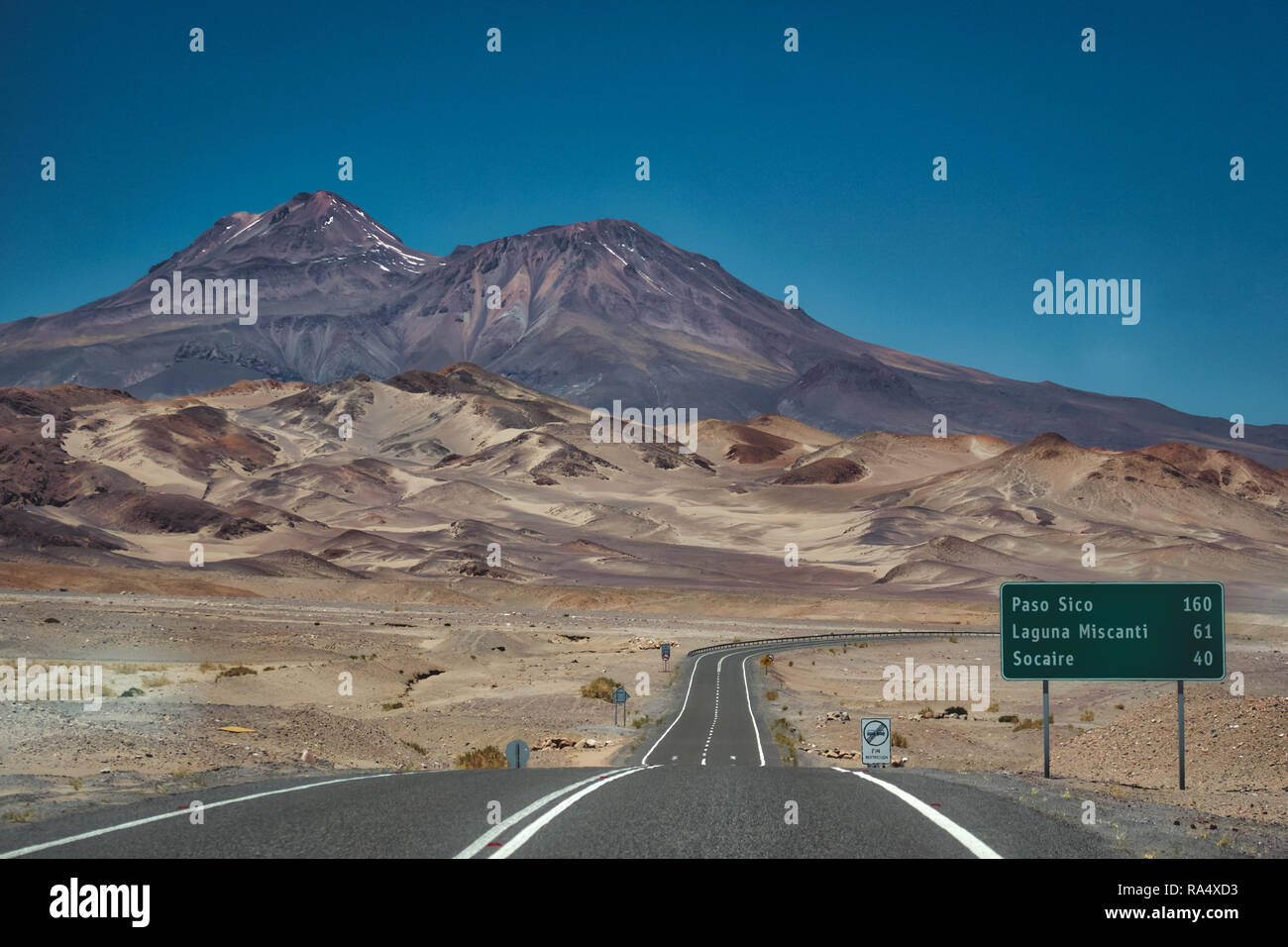 Teerstraße mit Wegweiser und zerklüftete Berge in der Atacama-wüste, Chile, Südamerika Stockfoto