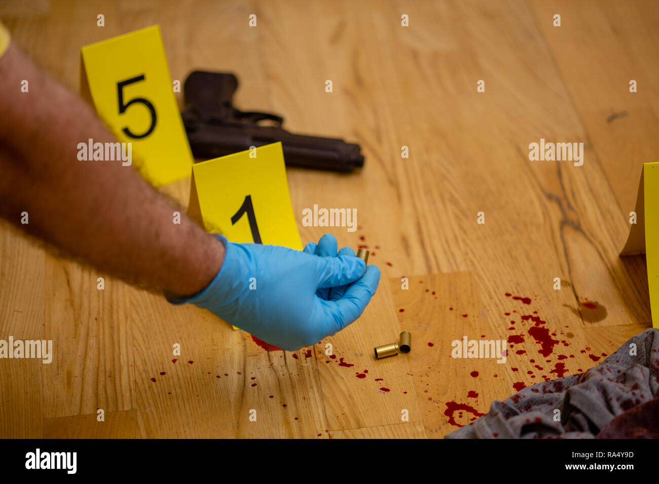 CSI forensices Investigator prüft bullet Gehäuse am Tatort Stockfoto