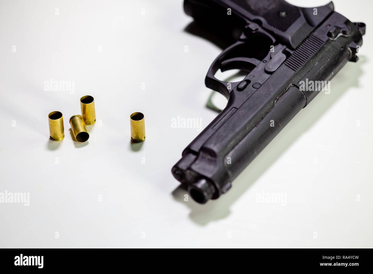 Pistole mit 9-mm-Patronenhülsen auf weißen Tisch Stockfoto