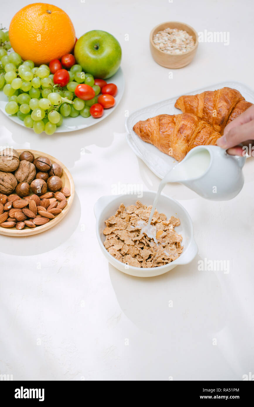 Licht gesundes Frühstück mit Haferflocken. Hercules, Nüsse, Obst, gekochte Eier, Brot. Gegenstände zum Tisch- und Küchengebrauch. Gesundes Essen. Stockfoto