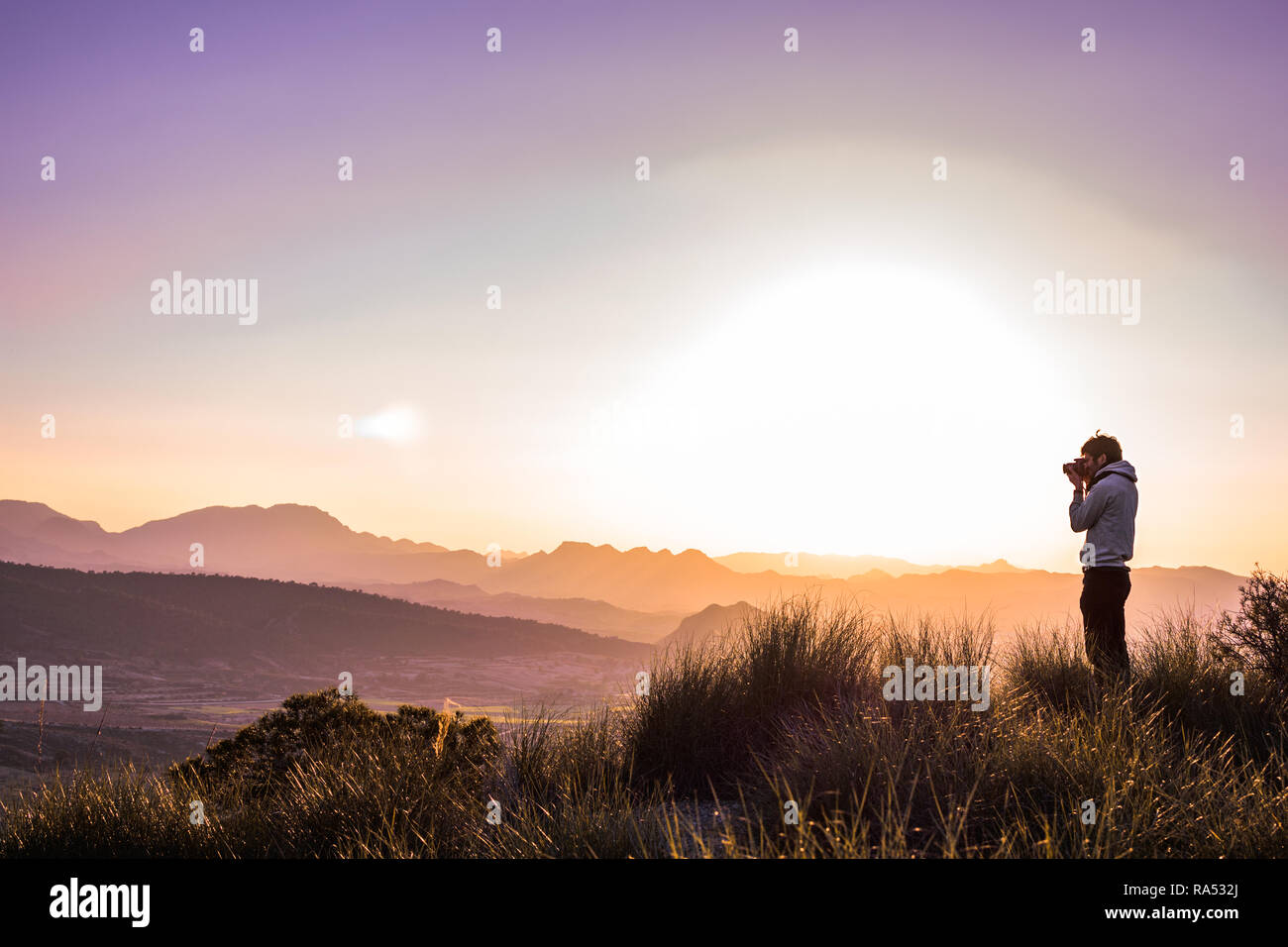 Mann an der Spitze eines Berges gegen nebligen Landschaft. Winter Aktivitäten im Freien. Lens Flares. Stockfoto