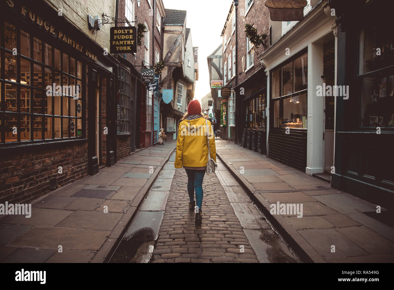 YORK, Großbritannien - 8. Dezember 2018. Eine Rückansicht eines Mädchens in Gelb auf einer Sightseeing Tour in The Shambles historische Straße in York, Großbritannien Stockfoto