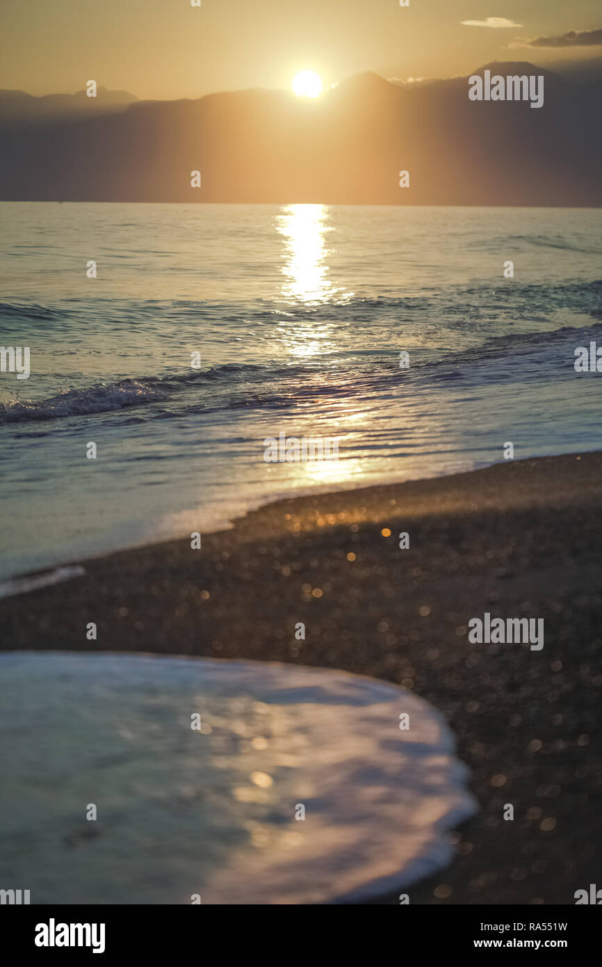 Golden Spritzer schäumenden Wellen im Meer bei Sonnenuntergang Himmel und weichen Sun hellen Hintergrund. Vertikale Farbfotografie. Stockfoto