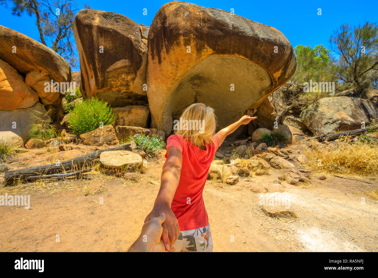 Folgen Sie mir, Frau, Hände halten in Hippo's Yawn, ein Hippo-geformten Felsen in der Nähe der Wave Rock in Hyden, australische Outback, Western Australia. Konzept der Reise von touristischen Reisenden, der Mann mit der Hand. Stockfoto