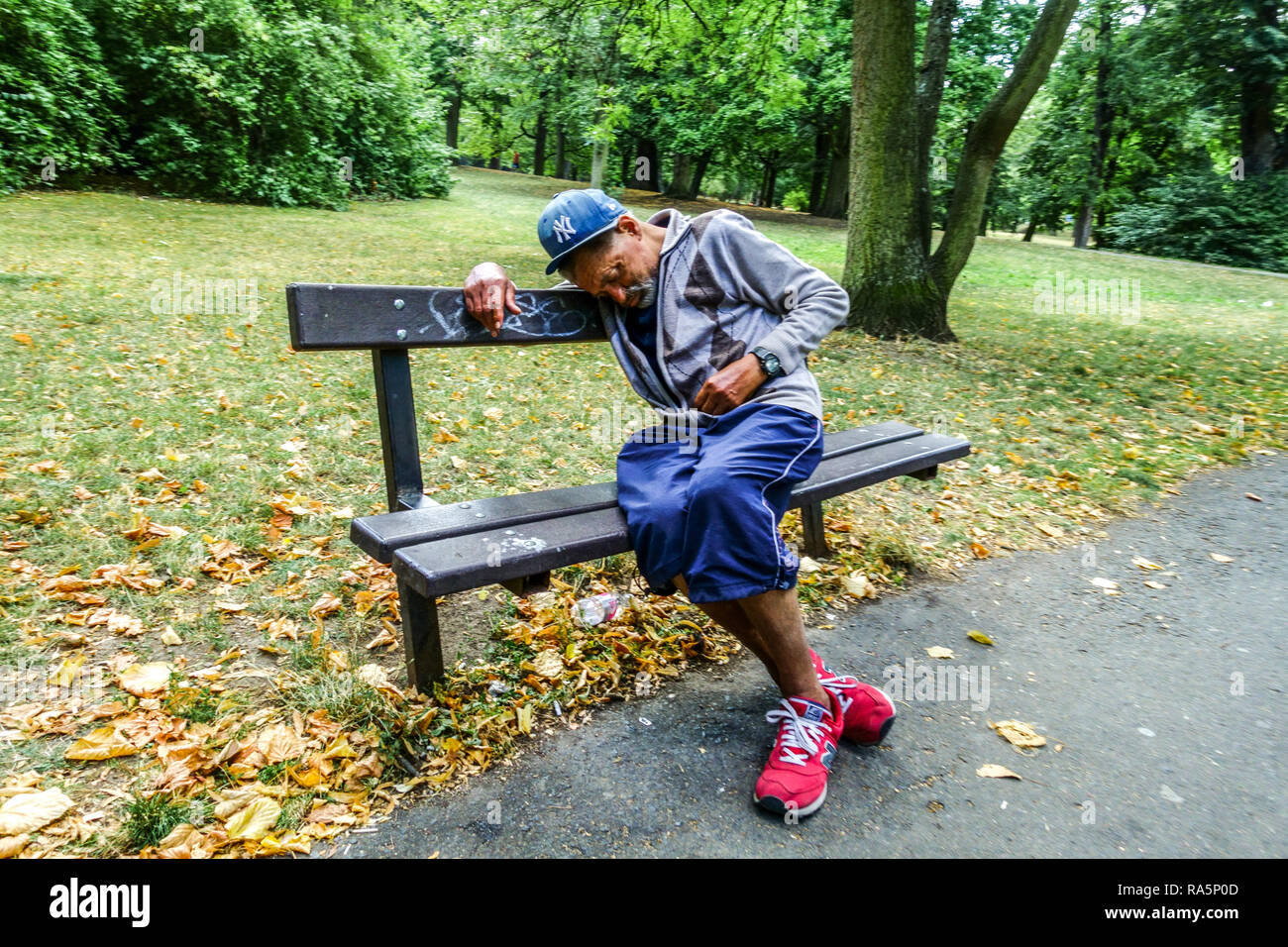 Älterer alter Mann auf einer Bank in einem Park Einsamkeit, ein Obdachloser in einem Stadtpark, müder älterer Mann Stockfoto