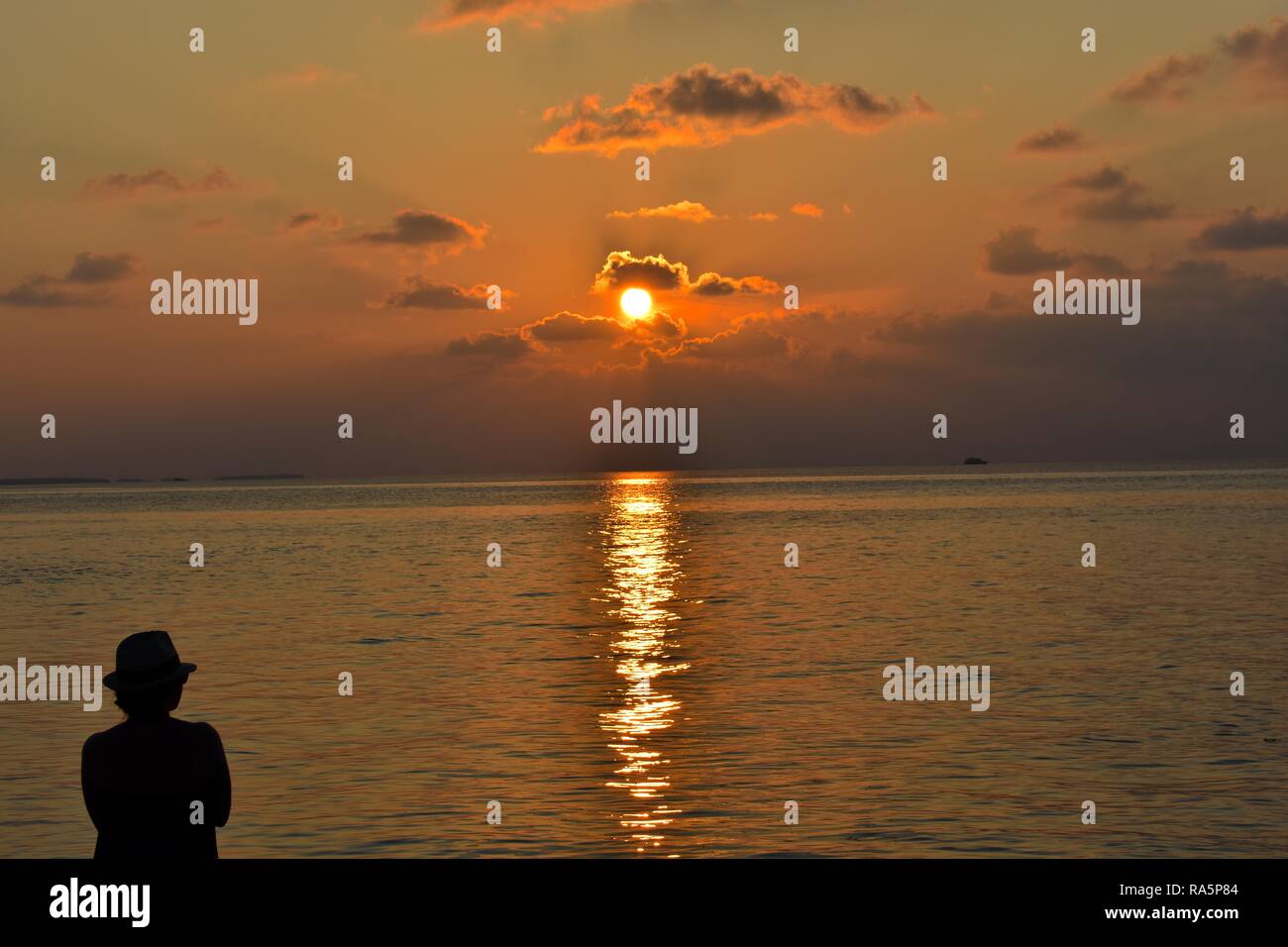 Frau mit Blick auf einen wunderschönen Sonnenuntergang im Paradies auf den Malediven, Indischer Ozean Stockfoto