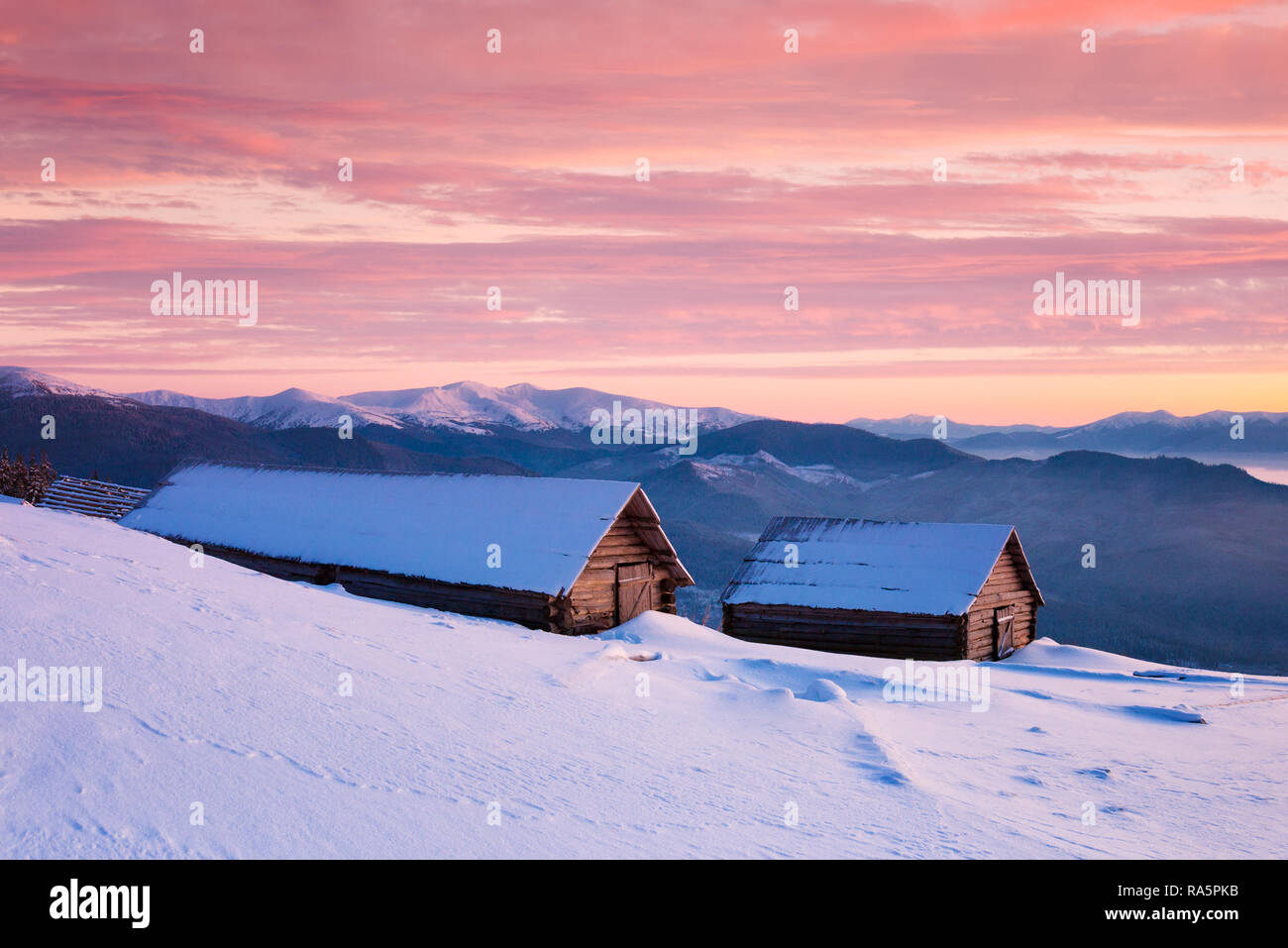 Winter frostigen Morgen mit dem schönen Sonnenaufgang. Berg Holzhütten mit Schnee bedeckt Stockfoto