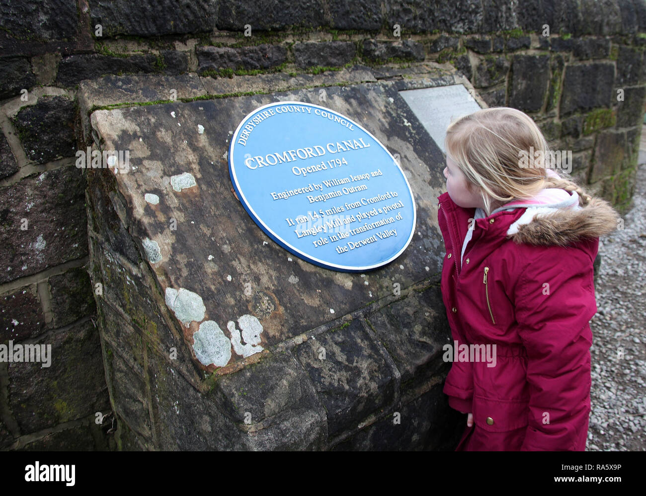 Kind neben einer blauen Plakette an der Seite von cromford Canal Stockfoto