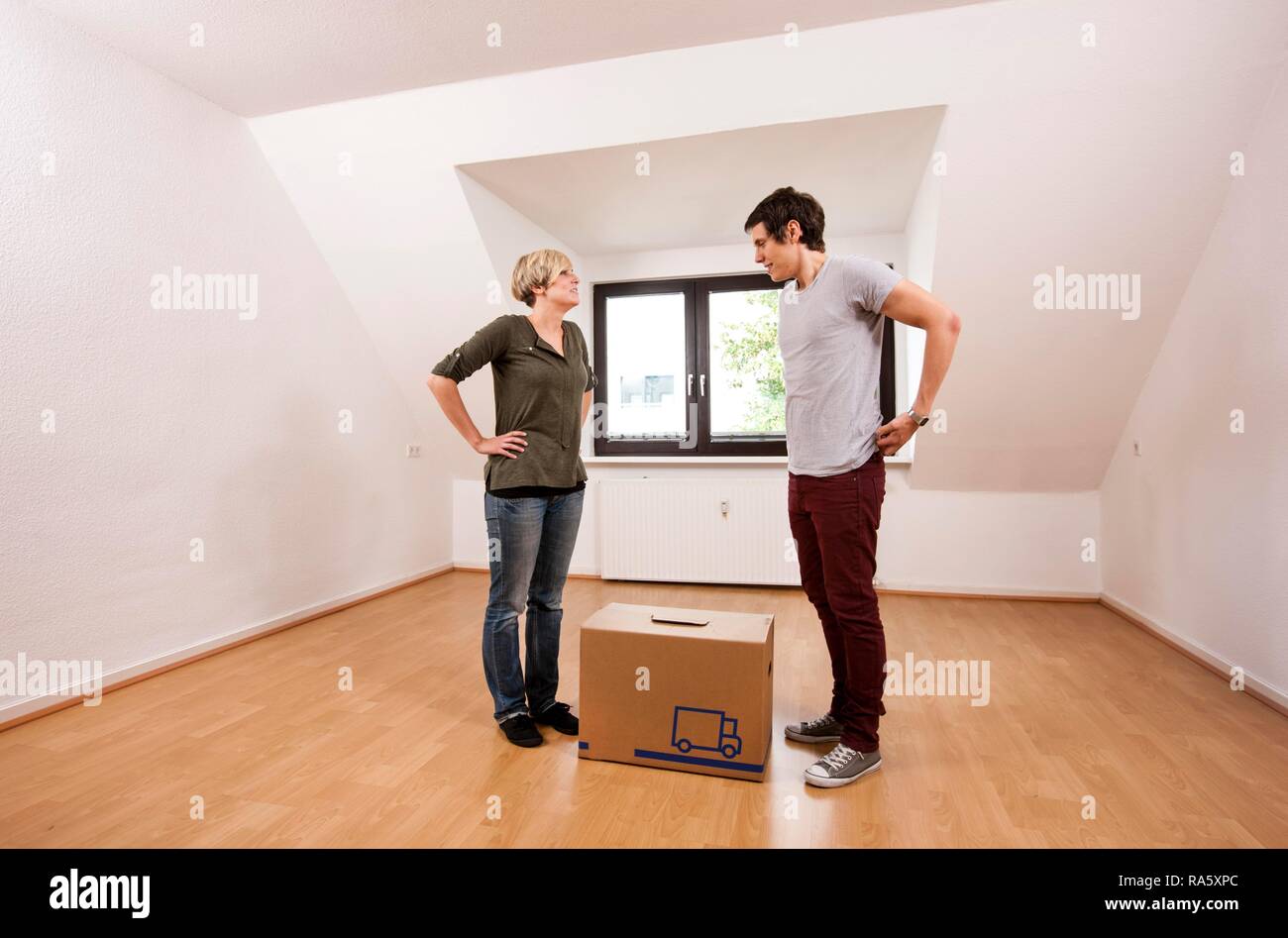 Junges Paar mit dem ersten Kasten in den leeren Wohnzimmer in eine neue Wohnung Stockfoto